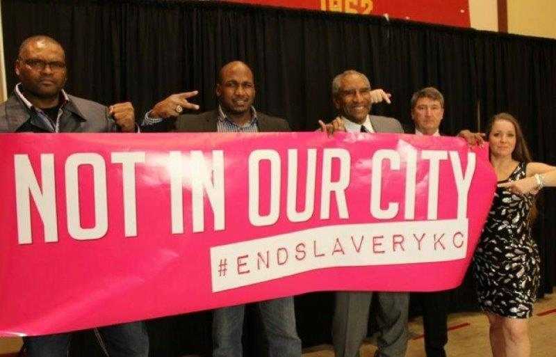 Kansas City Chiefs players and September Trible hold Not in Our City banner
